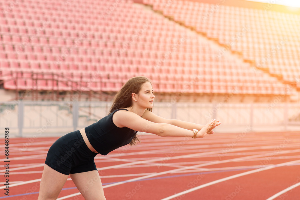 Young, beautiful girl athlete in sportswear is training at the stadium