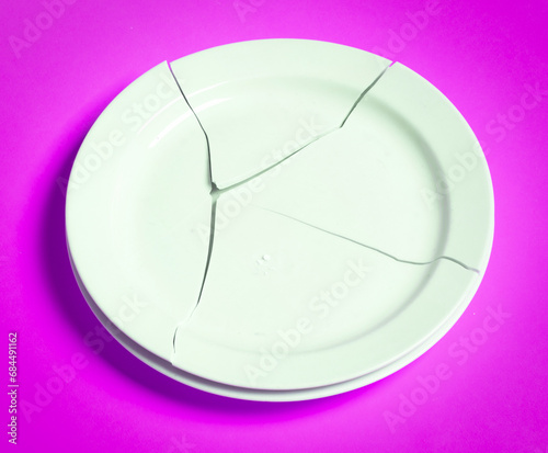 Broken white plate on a solid background