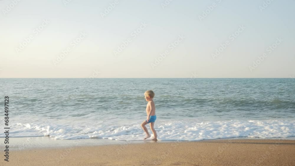 Happy childhood of a little boy 5 years old, who runs on the beach on the warm waves of the Mediterranean Sea. A child runs to the beach on seawater on a sunny hot summer day. High quality 4k footage Happy childhood of a little boy 5 years old, who runs on the beach on the warm waves of the Mediterranean Sea. A child runs to the beach on seawater on a sunny hot summer day. High quality 4k footage
