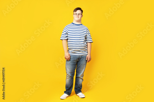 A boy with down syndrome in glasses on a yellow background
