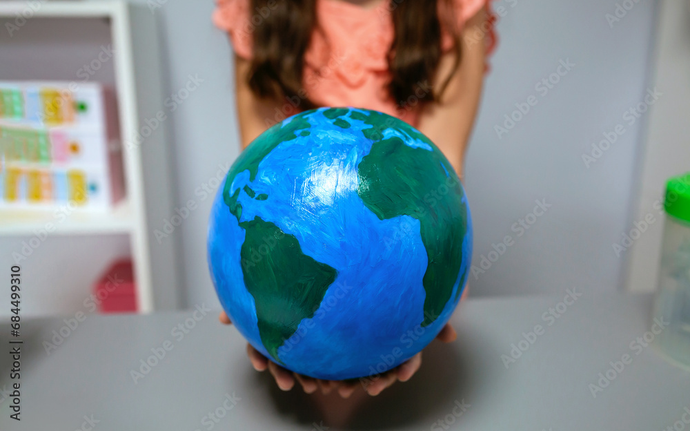 Unrecognizable female student showing in her hands a handmade globe world at ecology classroom. Sustainable lifestyle education concept. Unrecognizable female student showing in her hands a handmade globe world at ecology classroom. Sustainable lifestyle education concept.