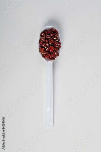 Red kidney beans on spoon on white background