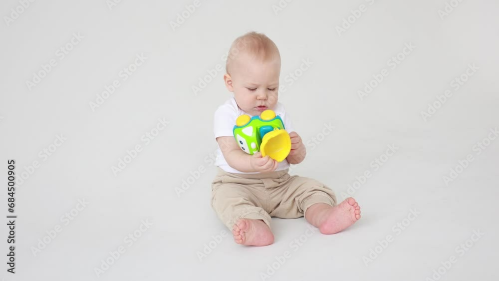 baby boy 8-9 months old sitting on a white background playing with a toy baby boy 8-9 months old sitting on a white background playing with a toy