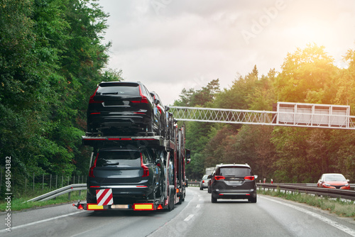 A tow truck carries a car on a flatbed trailer on the highway, providing transport service and assistance after an accident. photo