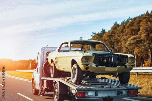 Vintage american muscle car body is on the flatbed towtruck after body works. Painting body of the car. Recover a Retro Car After an Accident. A Project to Restore a Classic Car with the Help of a Tow