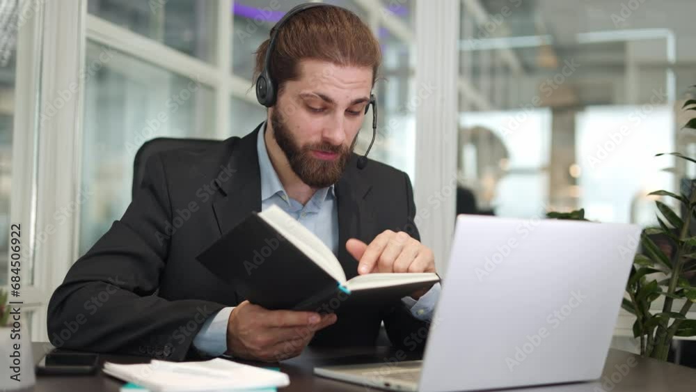 Handsome bearded male worker dressed in formal suit holding own notes and explaining them during video call with colleagues at workplace. Attentive businessman having online conversation indoors. Handsome bearded male worker dressed in formal suit holding own notes and explaining them during video call with colleagues at workplace. Attentive businessman having online conversation indoors.
