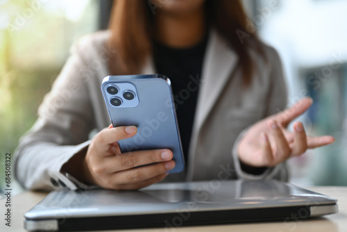 Young female employee sitting at desk and using mobile phone. Technology and lifestyle concept