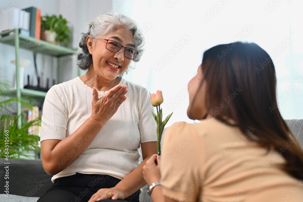 Grateful happy mature mother receiving flowers from grownup daughter. Happy Mothers Day concept Grateful happy mature mother receiving flowers from grownup daughter. Happy Mothers Day concept