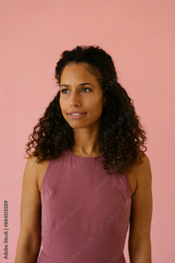 Woman with curly hair standing against pink background Woman with curly hair standing against pink background