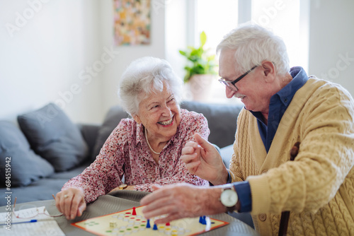 Happy senior couple playing ludo board game at home photo