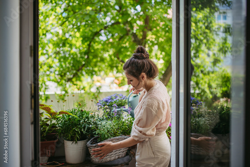 Woman watering flowers, taking care of plants on balcony