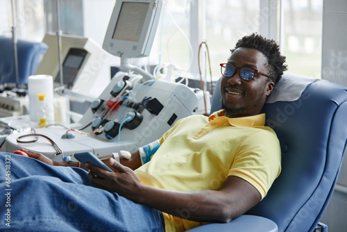 Smiling man donating blood lying on couch photo