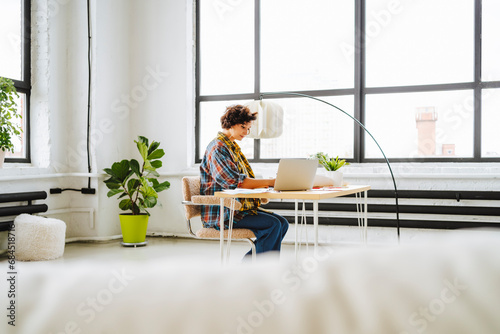 Young graphic designer working on laptop sitting at desk in office photo