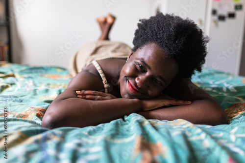 Smiling woman resting on bed in bedroom photo