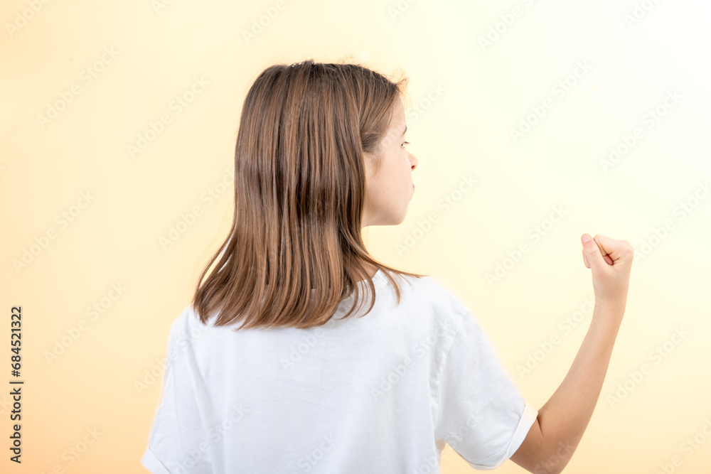 Teenager girl shows fist on yellow background isolated, side view. Teenager girl shows fist on yellow background isolated, side view.