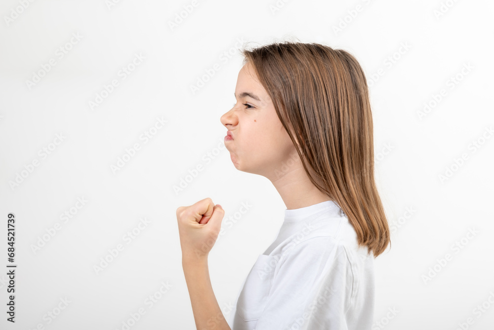 Teenager girl shows fist on white background isolated, side view. Teenager girl shows fist on white background isolated, side view.