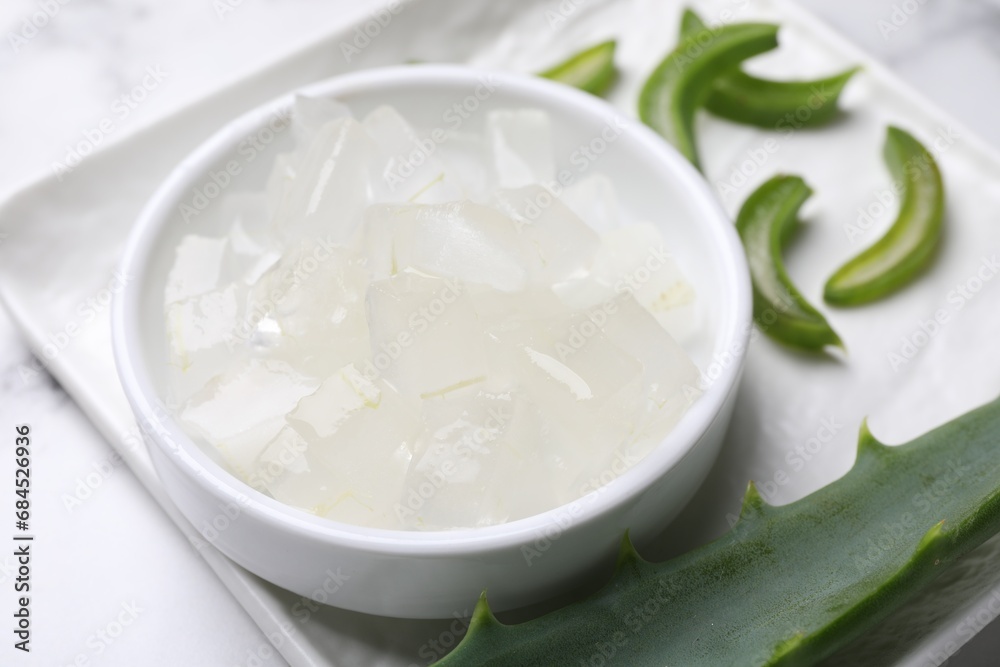 Aloe vera gel and slices of plant on white table, closeup Aloe vera gel and slices of plant on white table, closeup