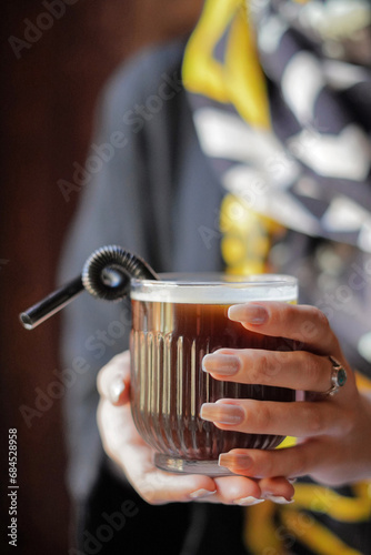 Woman Hands holding a cup of coffee with a straw