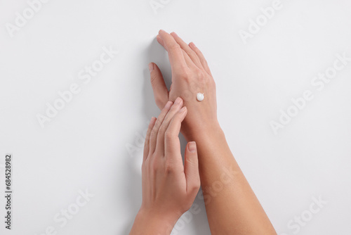 Woman with cosmetic cream on hand against white background  top view