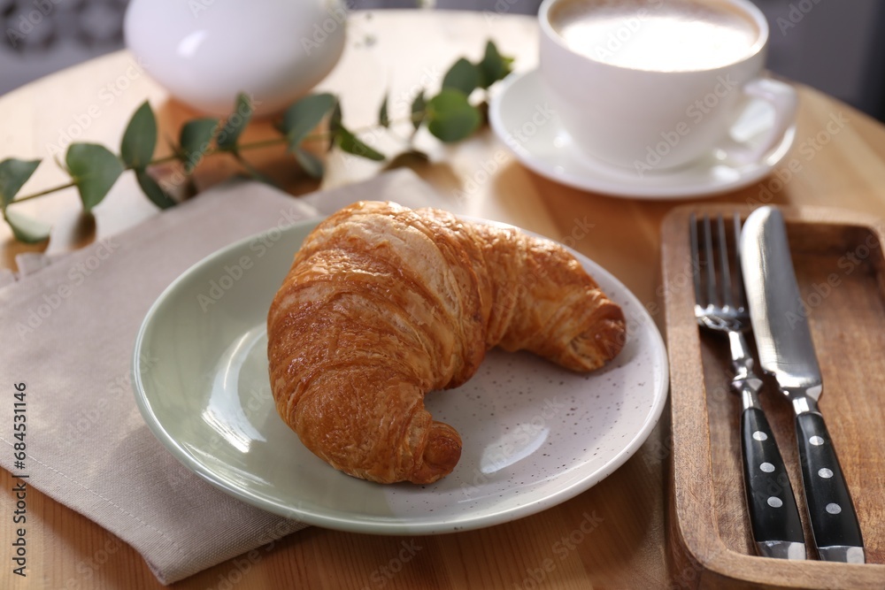 Tasty croissant served on wooden table, closeup Tasty croissant served on wooden table, closeup