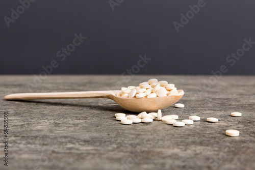 Heap of white pills on colored background. Tablets scattered on a table. Pile of red soft gelatin capsule. Vitamins and dietary supplements concept