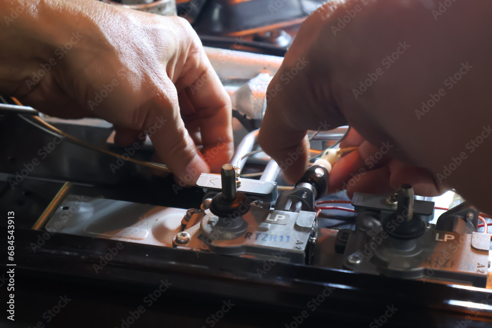 Close up of a technician's hand repairing a broken cooktop or stovetop Close up of a technician's hand repairing a broken cooktop or stovetop