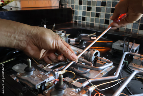 Close up of a technician's hand repairing a broken cooktop or stovetop