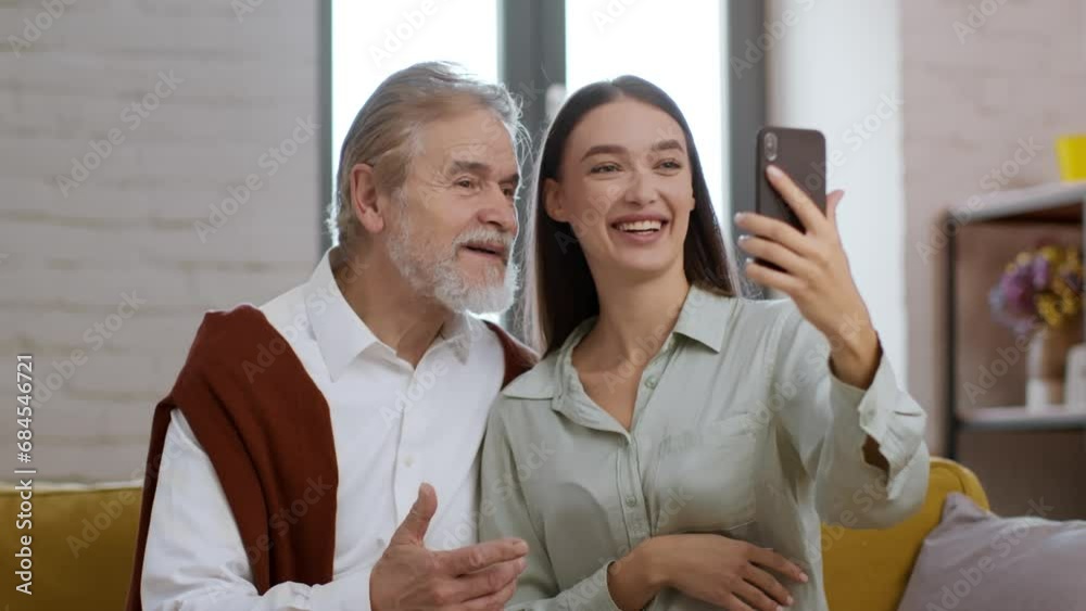 Young happy woman showing video chat app to her senior grandfather, calling to relatives, tracking shot, slow motion Young happy woman showing video chat app to her senior grandfather, calling to relatives, tracking shot, slow motion