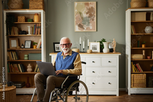 Elderly man in wheelchair using laptop
