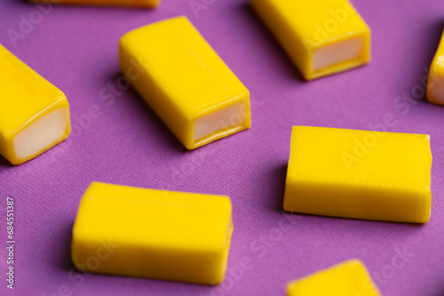 Tasty yellow bubble gums on purple background, closeup