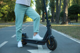 Woman with modern electric kick scooter in park, closeup