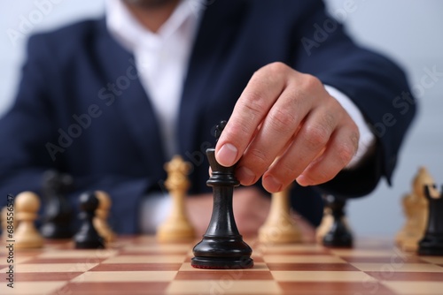 Man with king game piece playing chess at checkerboard, closeup