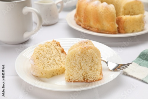 Pieces of delicious sponge cake and fork on white table, closeup