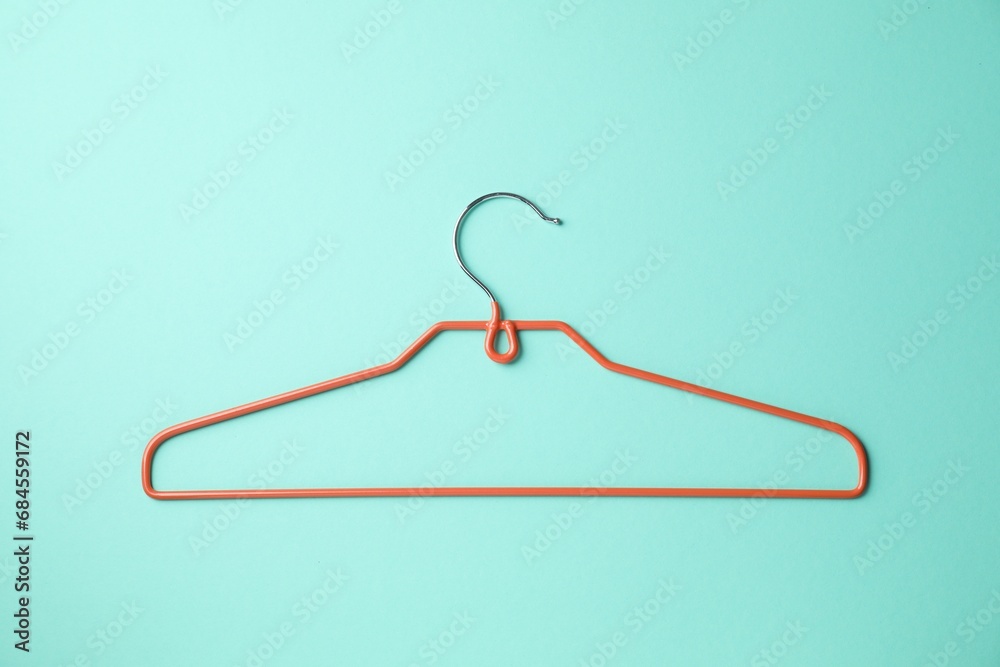 Empty orange hanger on turquoise background, top view