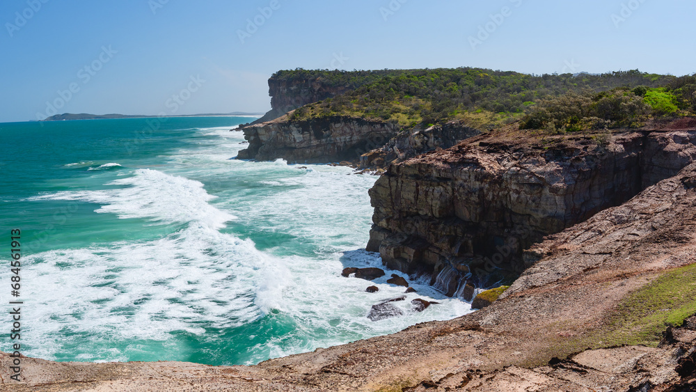 Australian coast, high cliffs on the seashore, seaside landscape with blue water, view from the cliff on a sunny summer day.