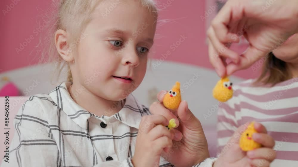 Girl child and mother plays with small knitted animal toys in a room at home Girl child and mother plays with small knitted animal toys in a room at home