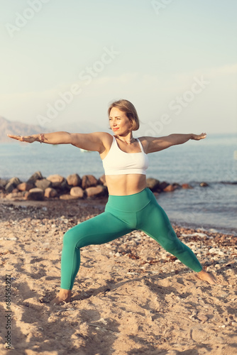 Warrior pose two on the beach young woman practice yoga
