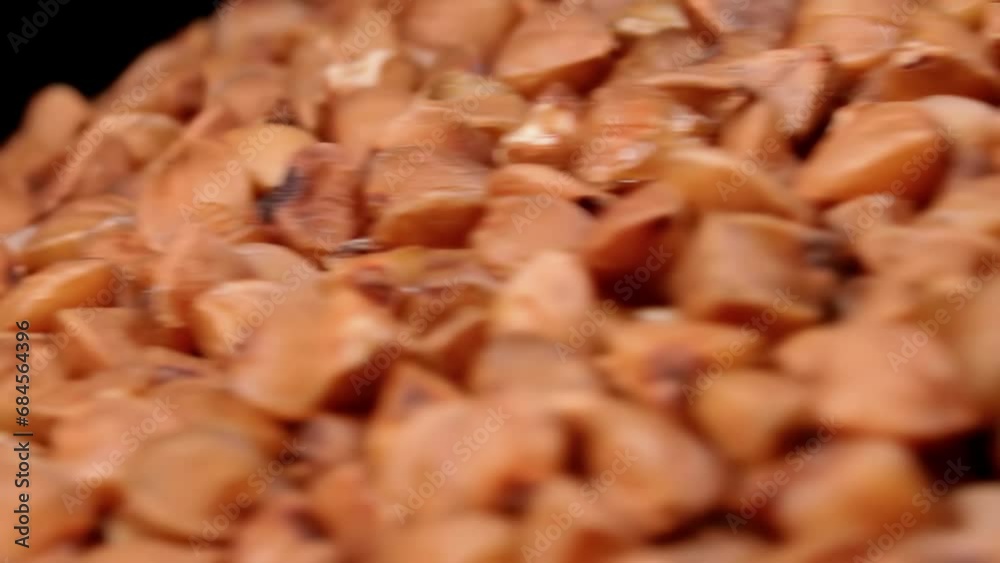 Dry Uncooked Brown Buckwheat Groats Heap on White Plate Rotating against Black Background - Macro. Raw Large Buckwheat Grains - Close-Up. Russian, Ukrainian and Belarusian Culture Dry Uncooked Brown Buckwheat Groats Heap on White Plate Rotating against Black Background - Macro. Raw Large Buckwheat Grains - Close-Up. Russian, Ukrainian and Belarusian Culture