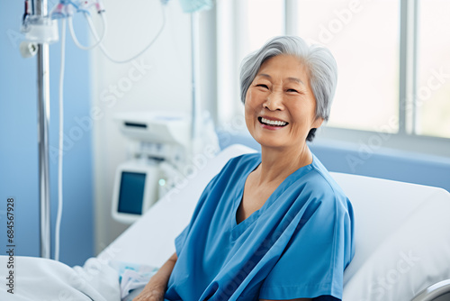Asian old female patient sitting and smiling on hospital bed