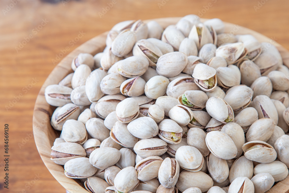 Pistachios in a wooden bowl. Wooden background. Healthy food