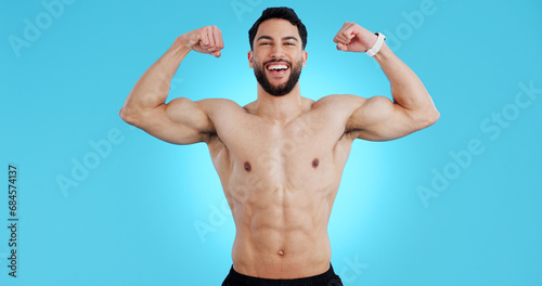 Happy man, portrait and muscle flex of bodybuilder in fitness isolated against a blue studio background. Male person, athlete or model smile showing strength, power or results for workout on mockup