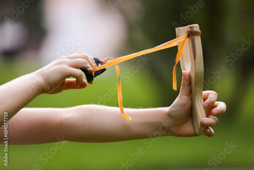 Little girl playing with slingshot outdoors, closeup photo