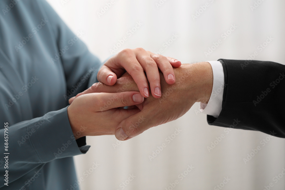Trust and deal. Man with woman joining hands on blurred background, closeup