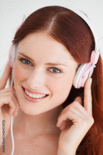 Smile, headphones and portrait of woman in a studio listening to music, playlist or album. Happy, excited and young female model from Canada streaming a song or radio isolated by white background.