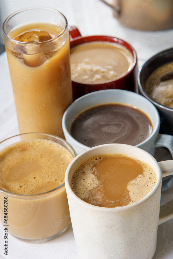 45 degree viev of several coffees. Some of them have milk, some are black, hot, iced, on a white tableccloth 45 degree viev of several coffees. Some of them have milk, some are black, hot, iced, on a white tableccloth
