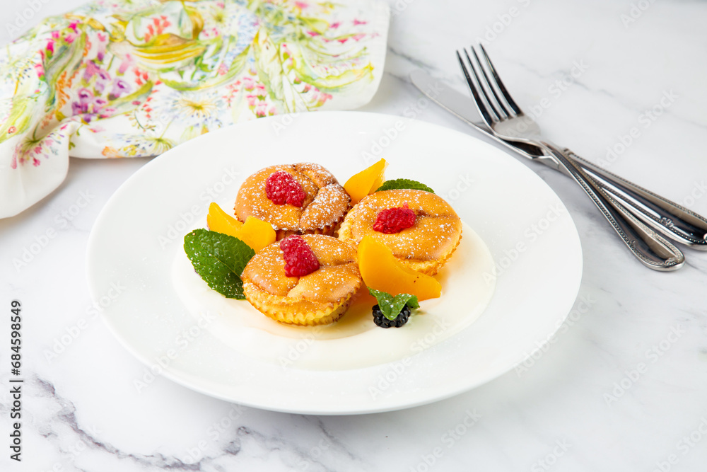 muffins with peach, raspberry, black berry and mint covered with powdered sugar, side view muffins with peach, raspberry, black berry and mint covered with powdered sugar, side view
