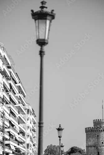 View of a lantern, residential buildings and the famous White Tower, also known as Lefkos Pyrgos in Thessaloniki Greece in black and white photo