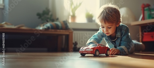 Cute little child boy playing with red big car toy sitting on the floor in his play room photo