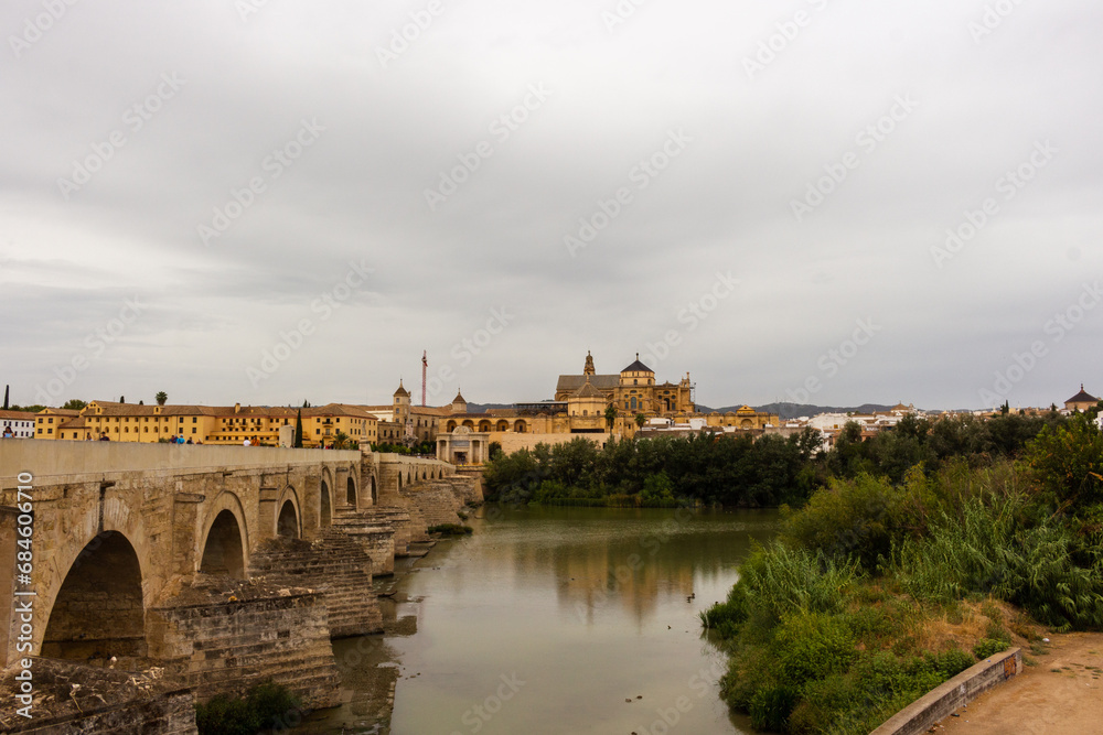 Cordoba, Spain, September 13, 2021: Guadalquivir River and the Roman Bridge, with Cordoba Mosque-Cathedral in the background.
