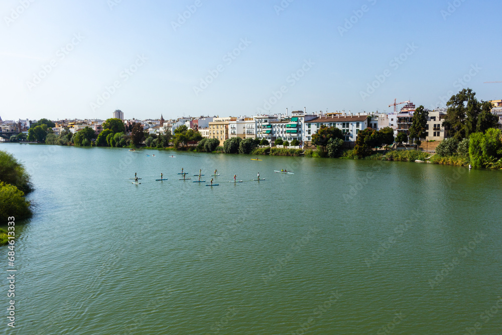 An instructor teaches paddle surfing to a group of children on the Guadalquivir river in Seville, Spain.